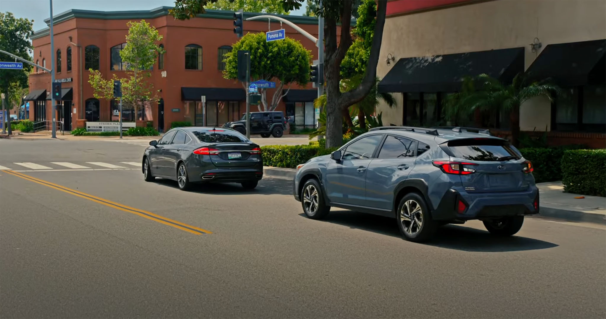 A Subaru stopped behind another car at an intersection.