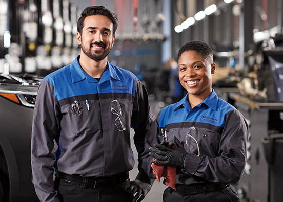 Two service technicians standing next to each other in a service bay.