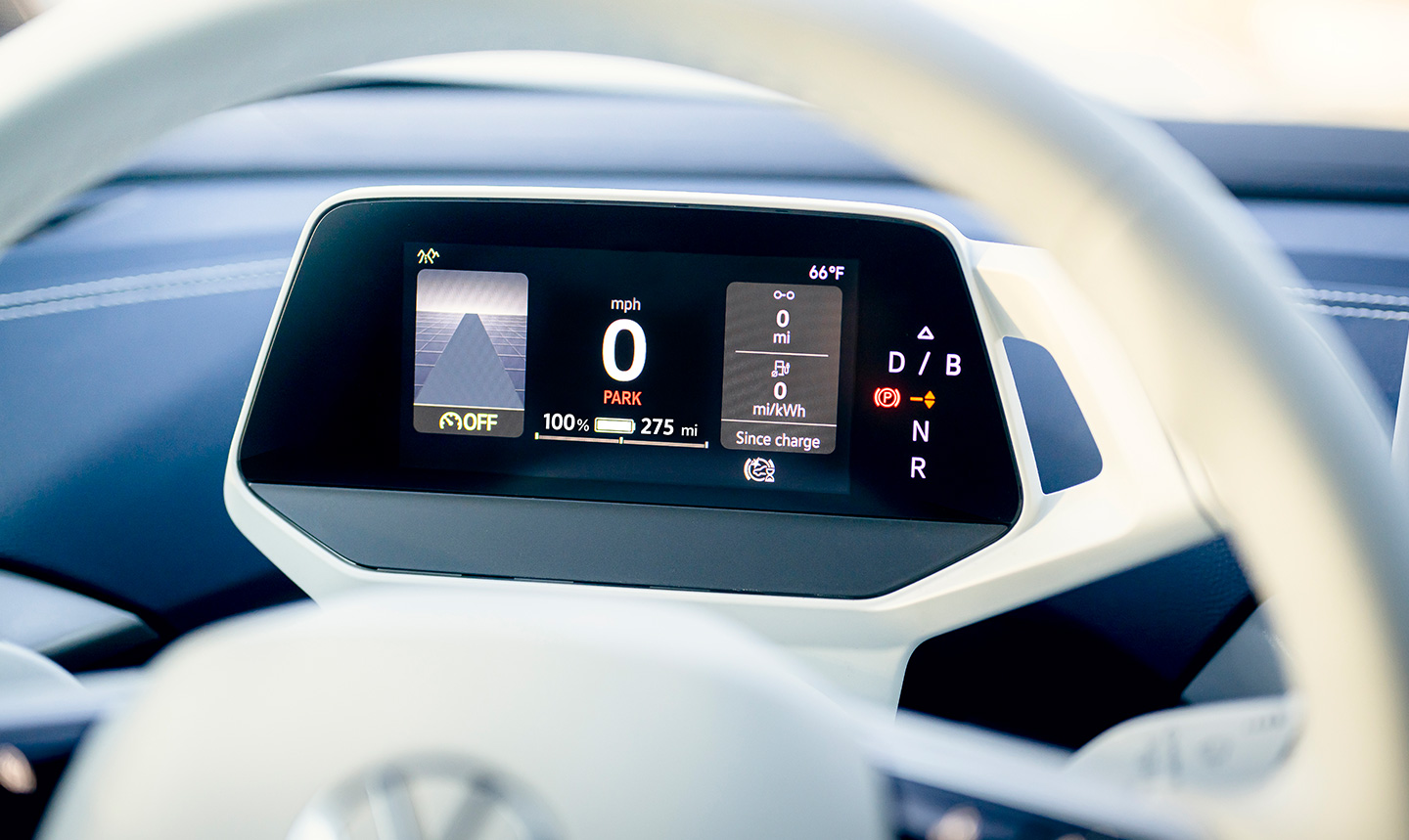 A close-up, of the Volkswagen ID.Cockpit digital instrument display behind the
            steering wheel, showing mile per hour and transmission gear graphics.