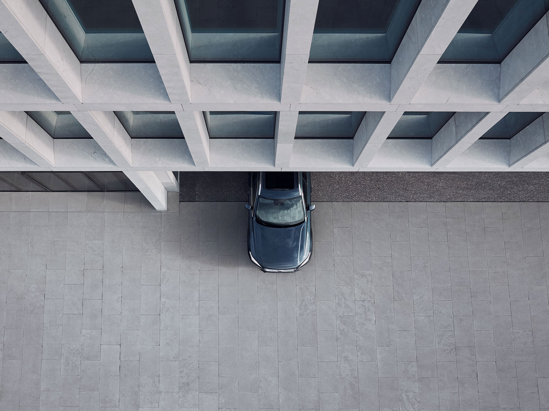 A bird’s-eye view of the front half of a Volvo car exiting from an urban building.