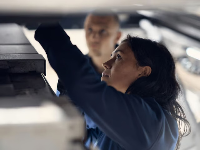 Female technician servicing underneath the car