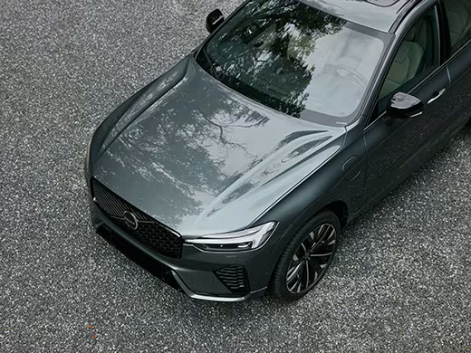 A high-angle shot of a Volvo plug-in hybrid SUV driving in Power mode across an ocean road.